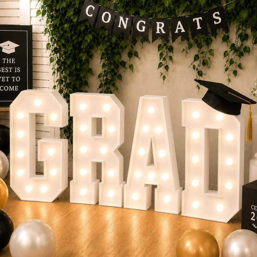 Graduation party decor with illuminated “GRAD” letters and cap banner