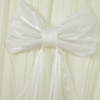 White satin bow on pleated fabric backdrop.