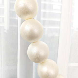 Cream-colored decorative spheres with textured surface hanging in a bright interior.