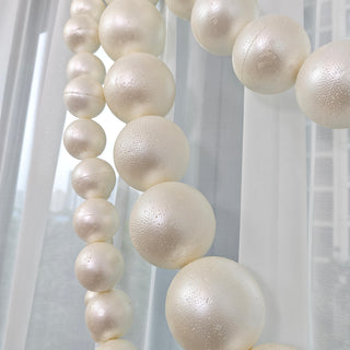 Cream pearl foam balls hanging in a soft white window garland decor
