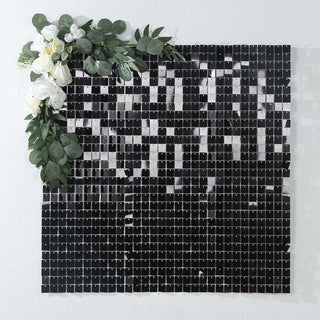 Decorative black mosaic wall art with artificial flowers and greenery.