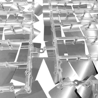 Clear plastic model kit parts arranged on a reflective surface.