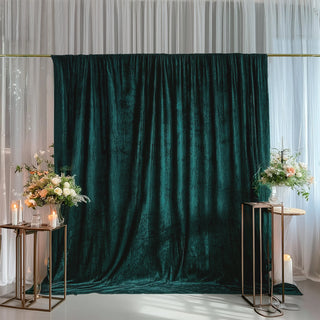 Elegant green velvet backdrop with floral arrangements and candles for events.