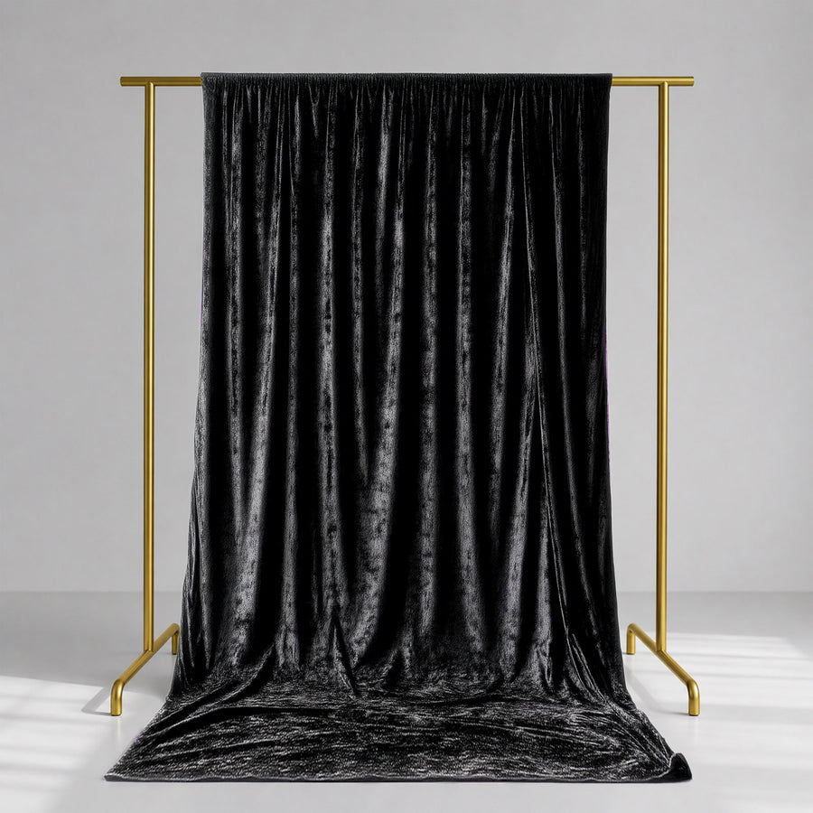 Black velvet curtain on gold clothing rack in minimalist studio setting