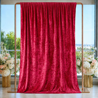 Red velvet backdrop curtain on gold stand with floral arrangements and windows