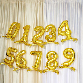 Gold balloon numbers 0 to 9 hanging against a curtain backdrop.
