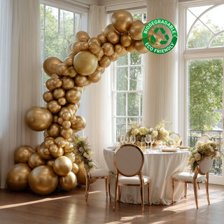 Elegant gold balloon arch decor in a bright venue with a stylish dining setup. #whtbkgd