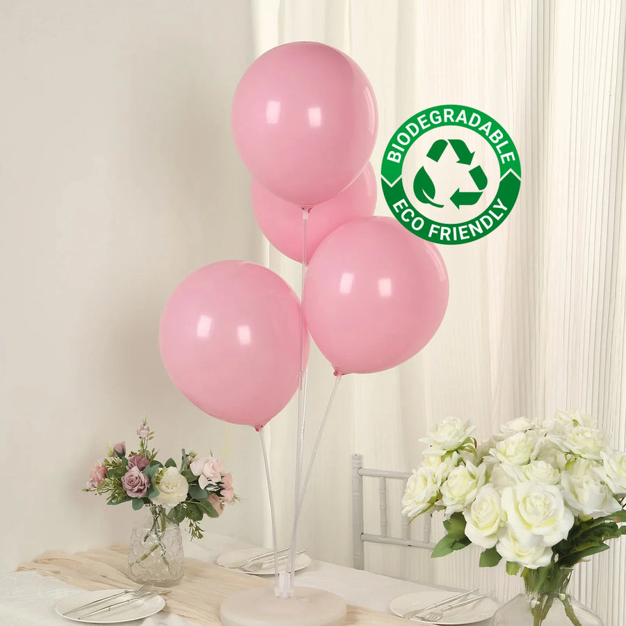 Pink biodegradable balloons on a table with flowers and eco-friendly label.