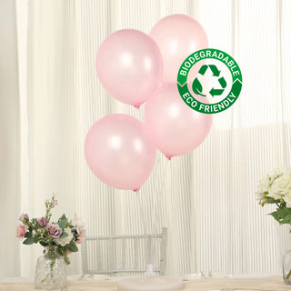 Eco-friendly biodegradable pink balloons on a table with flowers.