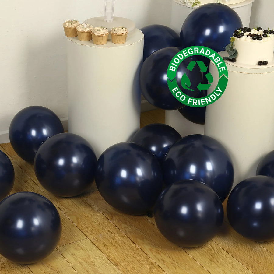 Biodegradable navy blue balloons scattered on a wooden floor with cupcakes in the background.