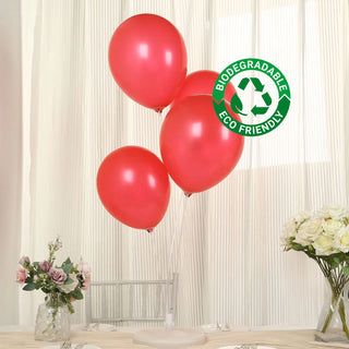 Red biodegradable balloons with eco-friendly label on a table.