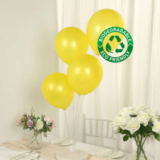 Yellow biodegradable balloons on a table with flowers and eco-friendly label.