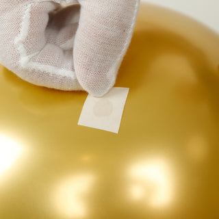 Gold balloon with a hand placing a label on it.