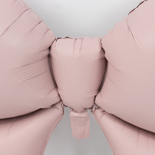 Pink balloon bow decoration on a plain background