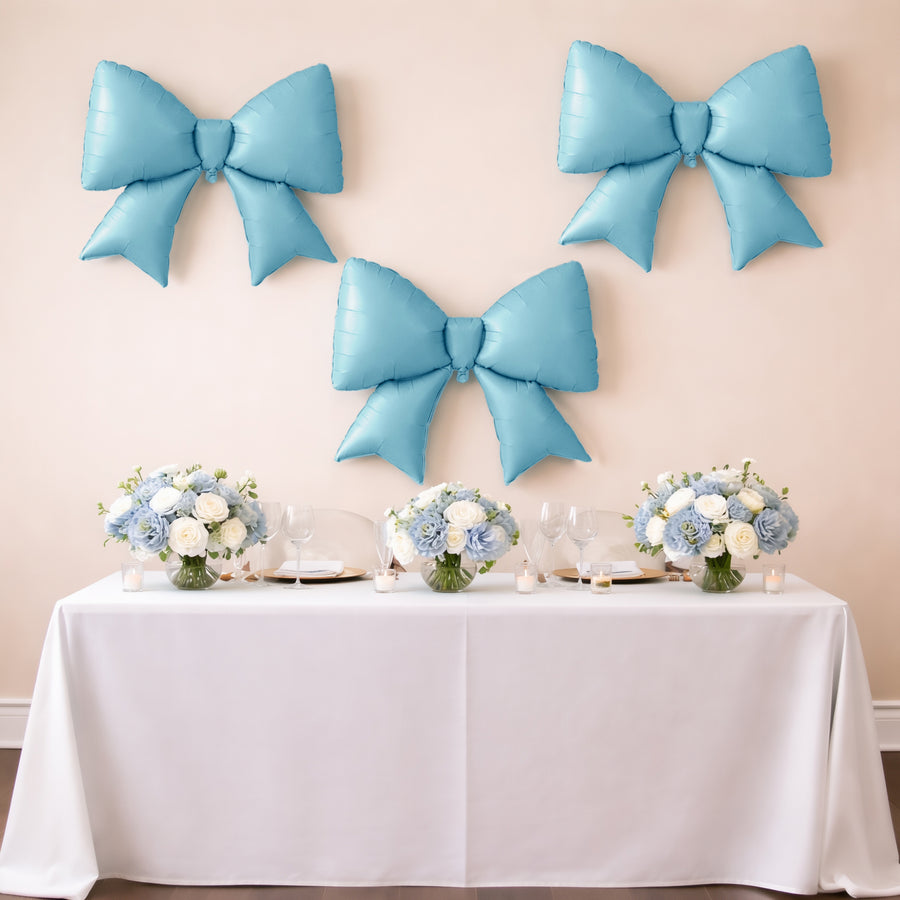 Blue balloon bows above a decorated table with floral arrangements and glassware.