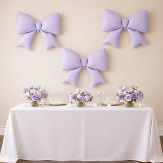 Purple balloon bows and floral centerpieces on a decorated table for an event.