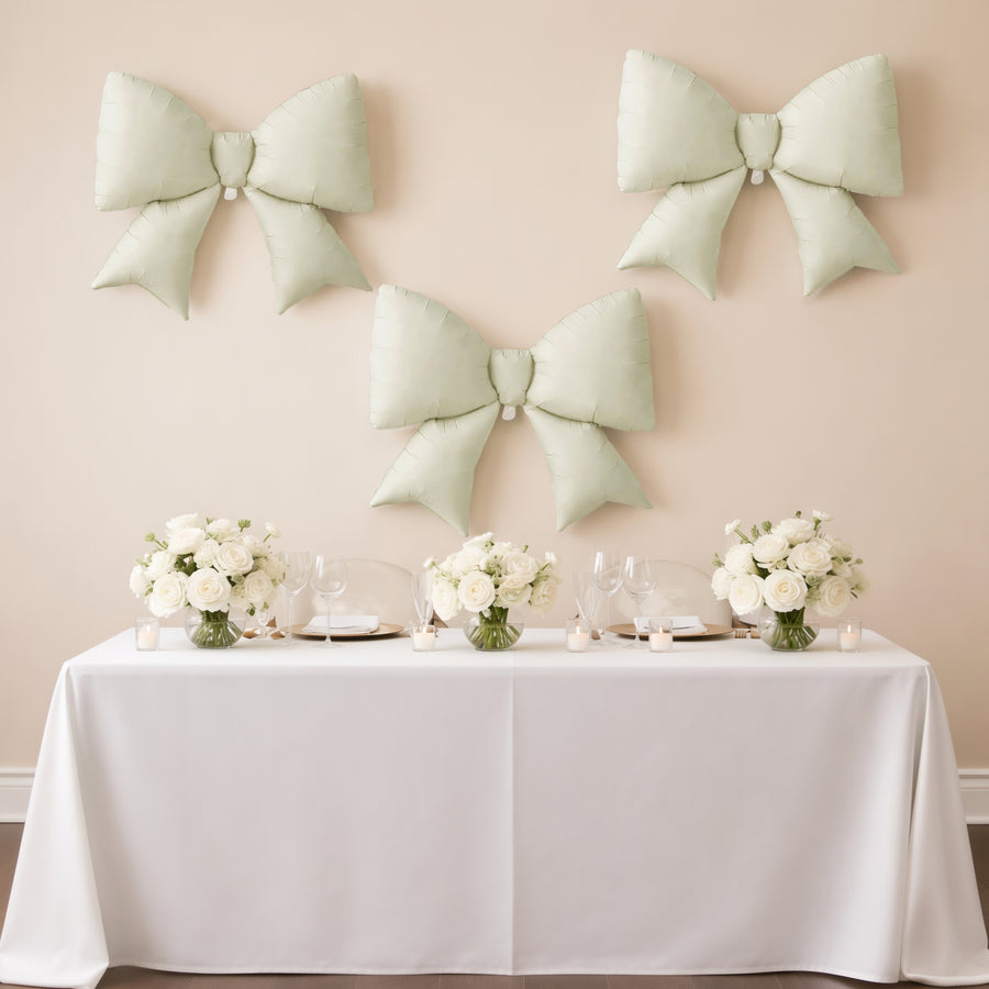 Elegant mint green bows on a wall above a beautifully set dining table with floral arrangements.