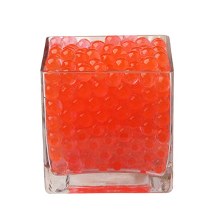 Orange decorative beads in a clear glass cube.