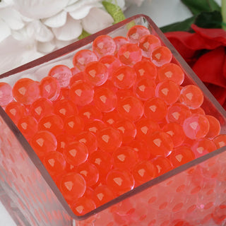 Vibrant red decorative water beads in a clear glass container.