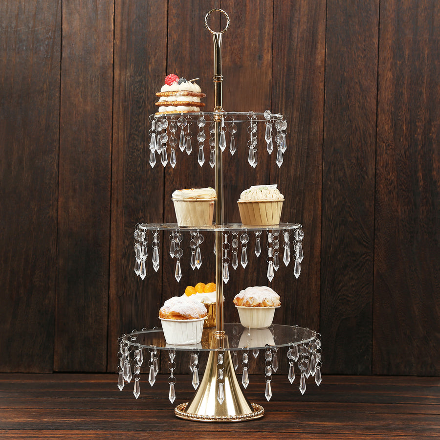Gold three-tiered cupcake stand with crystal accents and decorated pastries.