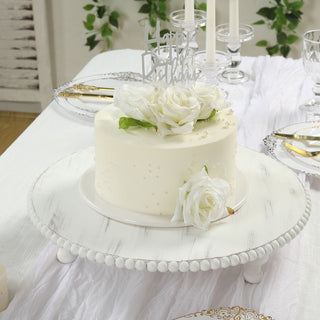 Birthday cake with white roses and decorative topper on a cake stand.