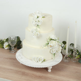 Elegant three-tier wedding cake adorned with white roses and greenery.