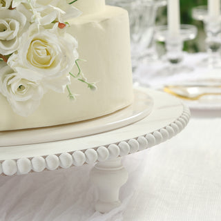 Elegant wedding cake adorned with white roses on a decorative cake stand.
