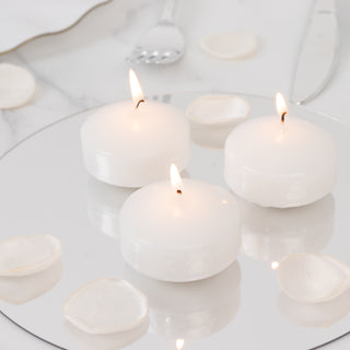 Three white candles with flames on a mirror surface, surrounded by petals.