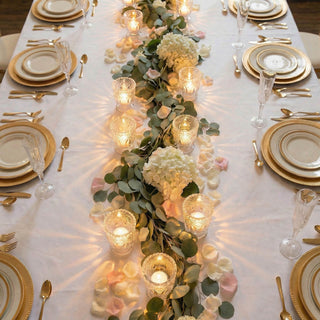 Elegant gold wedding table setting with floral eucalyptus centerpiece and candles
