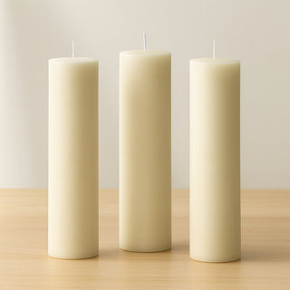 Three ivory pillar candles in varying heights on a wooden surface.