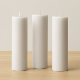 Set of three white pillar candles on a wooden surface.