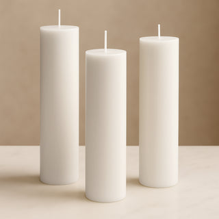 White pillar candles in varying heights against a soft beige background.