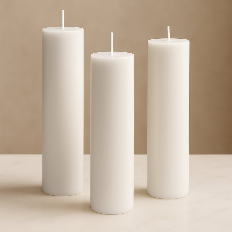 White pillar candles in varying heights against a soft beige background.