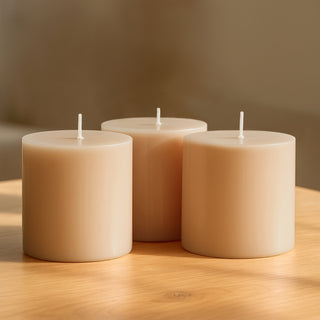Three beige candles on a wooden table.