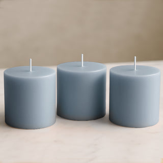 Three blue pillar candles on a marble surface.