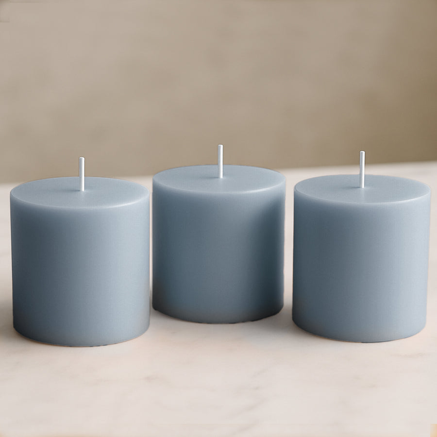 Three blue pillar candles on a marble surface.
