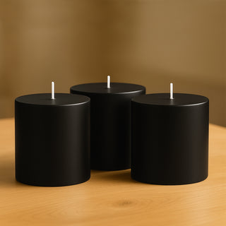 Black cylindrical candles on a wooden table.