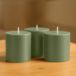 Three green cylindrical candles on a wooden table.