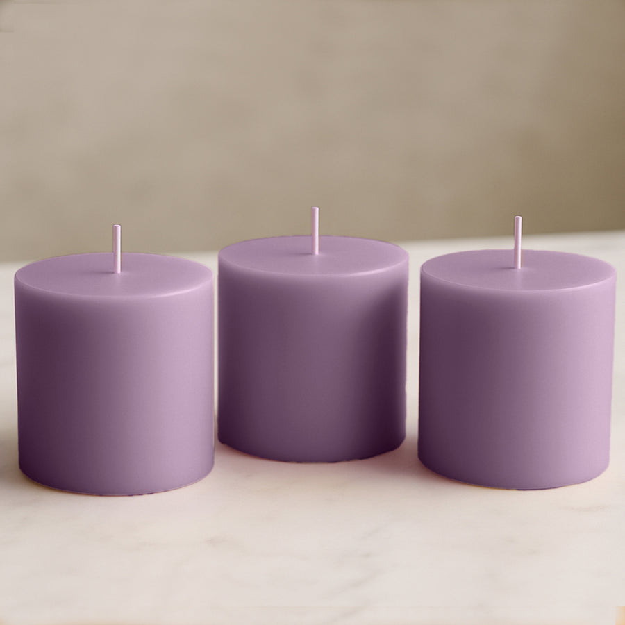 Purple pillar candles set on a marble surface.