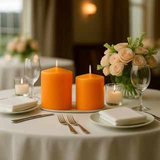 Orange candles on a dining table with flowers and glassware in a restaurant setting.