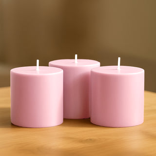 Pink decorative candles in varying heights on a wooden surface.
