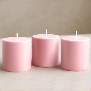 Pink cylindrical candles in a trio arrangement on a marble surface.