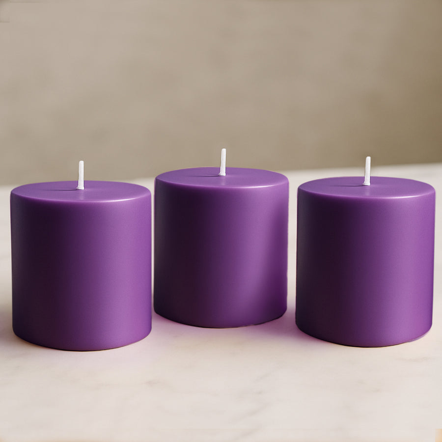 Purple pillar candles in varying heights on a marble surface.