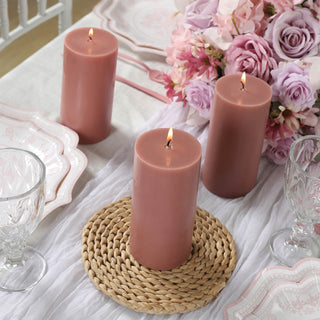 Three pink candles on a table with flowers and elegant dinnerware.