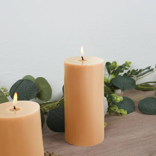 Orange pillar candles with greenery in a cozy setting.