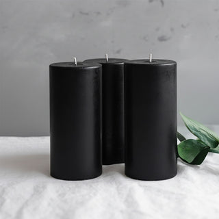 Black pillar candles grouped together on a neutral background.