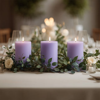 Lavender candles surrounded by greenery on a beautifully set dining table.
