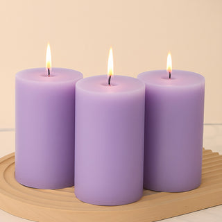 Lavender pillar candles with flames on a wooden tray
