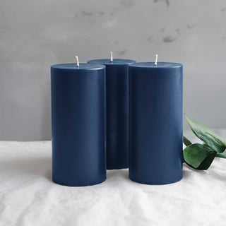 Three navy blue pillar candles on a light fabric surface.