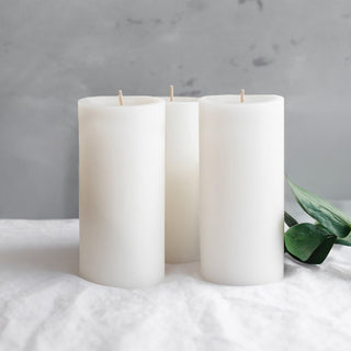 Set of three white pillar candles with a green leaf accent.